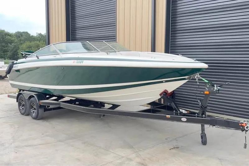 Slide: The Image of 2000 Cobalt 252 boat on trailer, parked near a building with black shutters. - 1