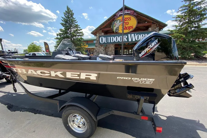 Slide: The Image of 2026 Tracker Pro Guide V-16 SC boat outside Bass Pro Shops, featuring Mercury engine. - 2