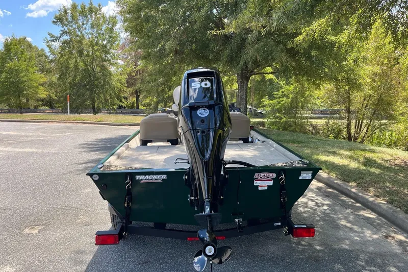 Slide: The Image of 2026 Tracker Bass Tracker Classic Limited boat with motor, parked outdoors under trees. - 4