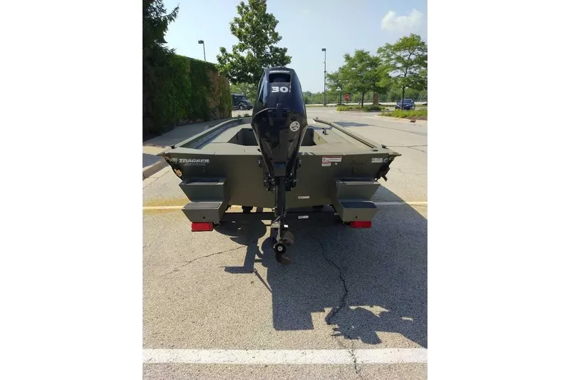Slide: The Image of 2026 Tracker Grizzly 1654 T Sportsman boat, rear view with motor, parked outdoors. - 3