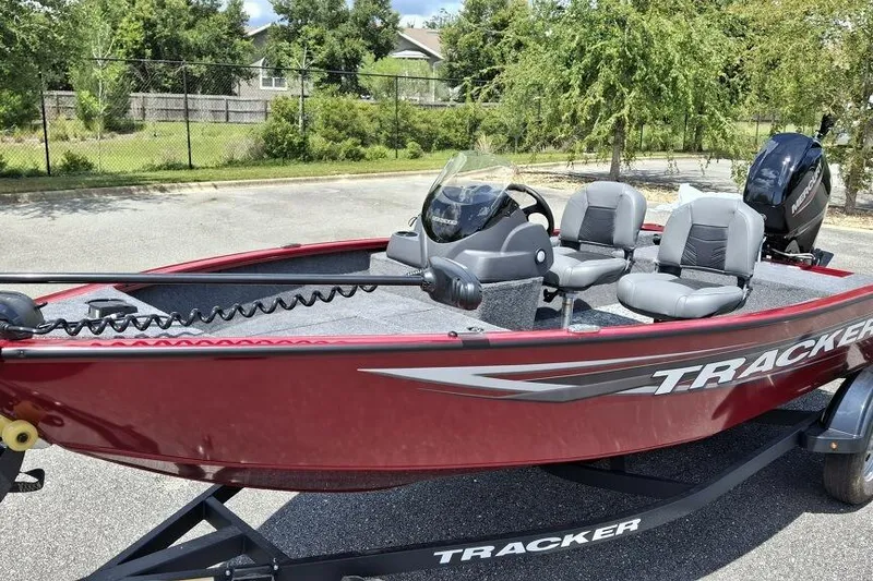 Slide: The Image of 2026 Tracker Super Guide V-16 SC boat, red exterior, parked outdoors, featuring dual seats and steering console. - 2