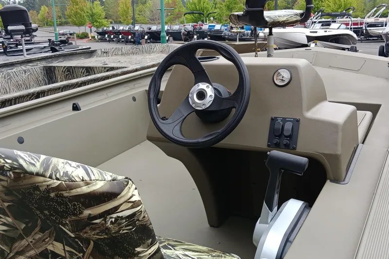 Slide: The Image of 2026 Tracker Grizzly 1754 SC boat interior with camo seats and steering console. - 2