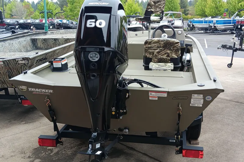 Slide: The Image of 2026 Tracker Grizzly 1754 SC boat with Mercury 60 engine, camo seats, parked outdoors. - 3
