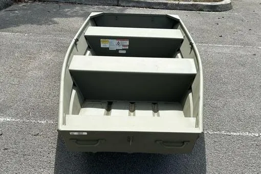 Slide: The Image of 2026 Tracker Grizzly 12 Jon boat, parked on asphalt, showcasing interior seating and storage. - 2