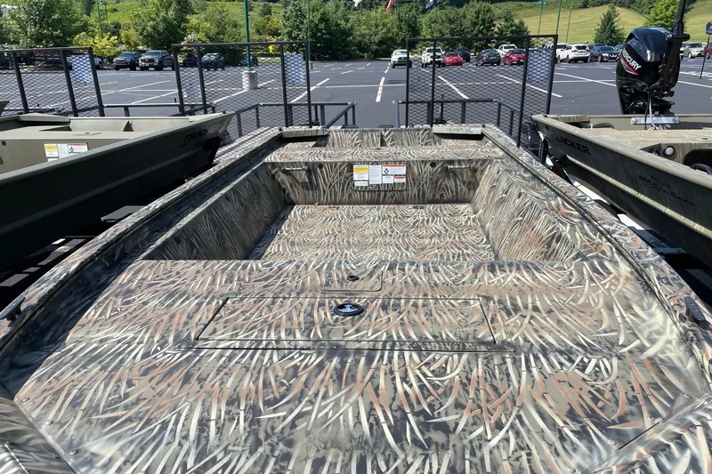 Slide: The Image of 2026 Tracker Grizzly 1648 Utility boat with camouflage design in a parking lot. - 2