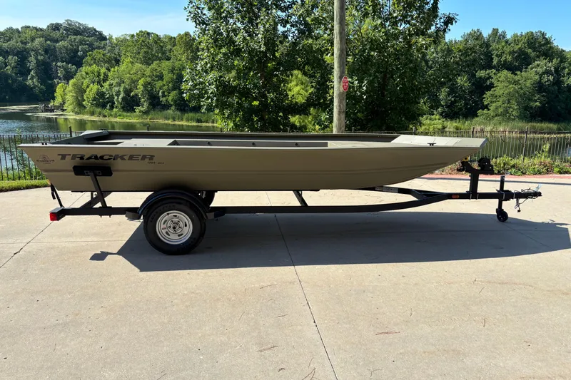 The Image of 2026 Tracker Grizzly 1754 Utility boat on trailer, parked near a scenic lake. - 0