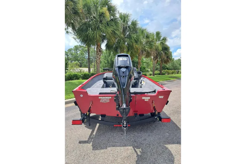 Slide: The Image of 2026 Tracker Super Guide V-16 SC boat with outboard motor, parked near palm trees. - 5