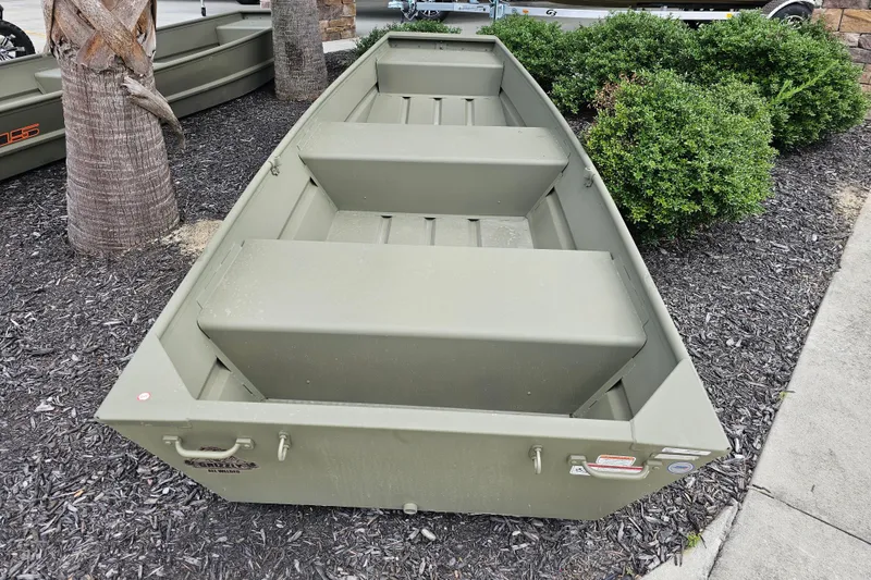 Slide: The Image of 2026 Tracker Grizzly 12 Jon boat in outdoor display, surrounded by mulch and greenery. - 5