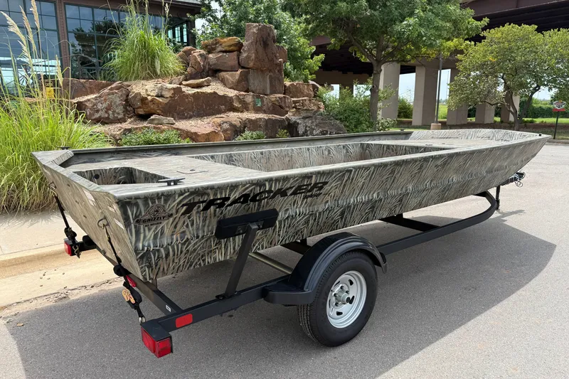 Slide: The Image of 2026 Tracker Grizzly 1860 Utility boat on trailer, camo design, parked outdoors. - 4