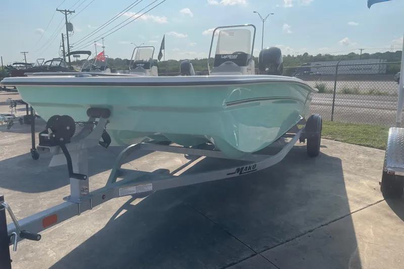 Slide: The Image of 2026 Mako Pro Skiff 17 CC boat on trailer, parked outdoors under clear sky. - 2