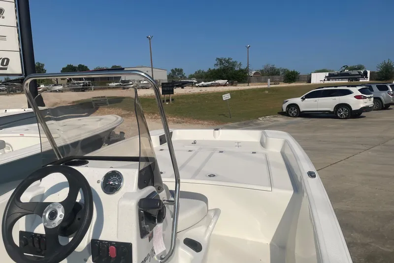 Slide: The Image of 2026 Mako Pro Skiff 17 CC boat with steering wheel, parked in a lot under clear blue sky. - 9