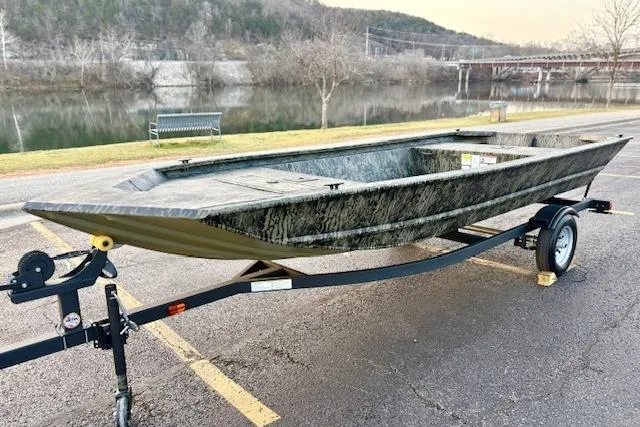 Slide: The Image of 2026 Tracker Grizzly 1648 Utility boat on trailer by a riverside park. - 2