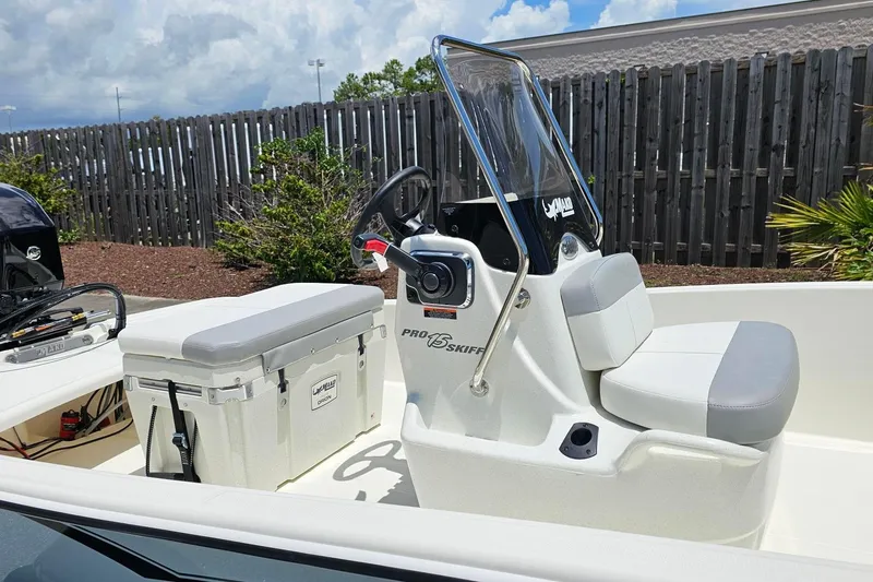 Slide: The Image of 2026 Mako Pro Skiff 15 CC boat with seating and console, parked outdoors. - 10