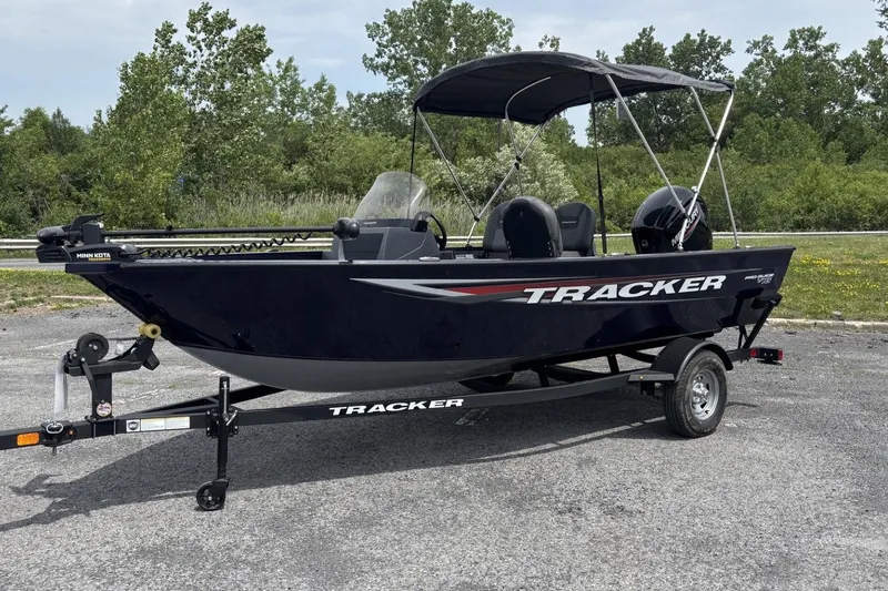 The Image of 2026 Tracker Pro Guide V-16 SC boat with canopy on trailer, parked outdoors. - 0