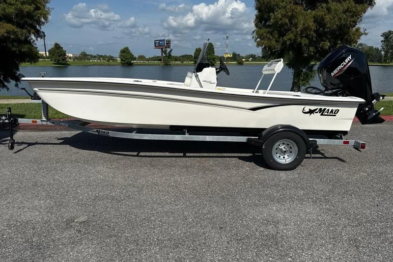 The Image of 2026 Mako Pro Skiff 17 CC boat on trailer by a lake under a blue sky. - 0