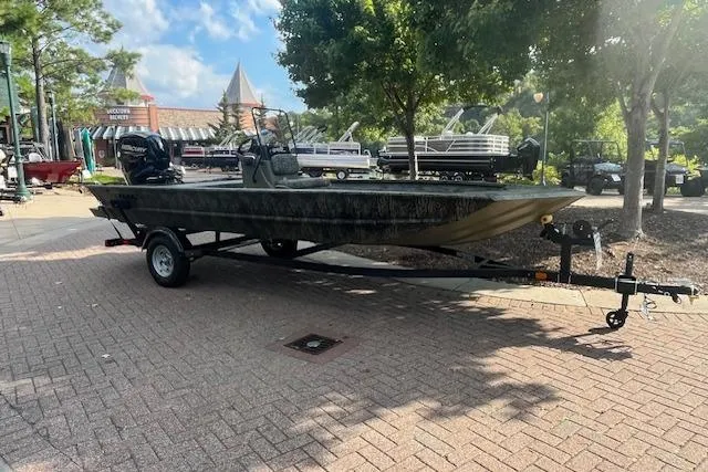 The Image of 2026 Tracker Grizzly 1860 CC boat on trailer, parked outdoors under trees. - 0