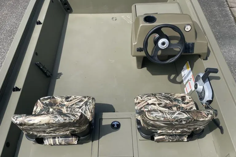 Slide: The Image of 2026 Tracker Grizzly 1754 SC boat interior with camo seats and steering console. - 2