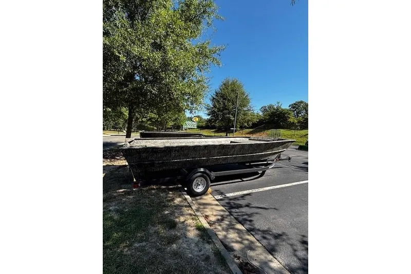 Slide: The Image of 2026 Tracker Grizzly 2072 Utility boat on trailer in parking lot, surrounded by trees. - 3