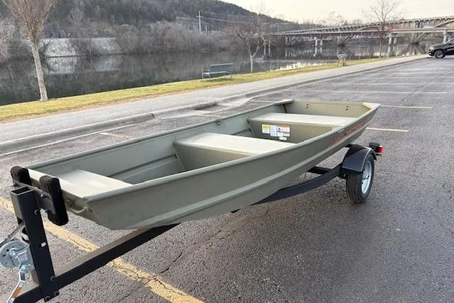 Slide: The Image of 2026 Tracker Grizzly 12 Jon boat on trailer, parked near a scenic river. - 2