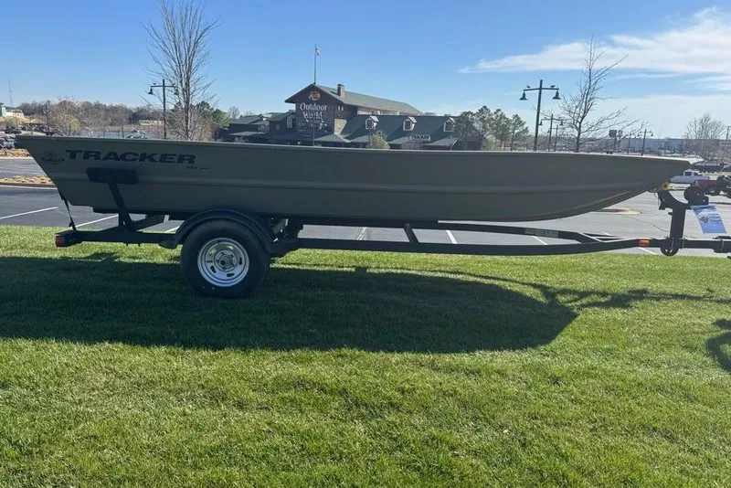 Slide: The Image of 2026 Tracker Grizzly 1754 Utility boat on trailer, parked on grass near outdoor store. - 2