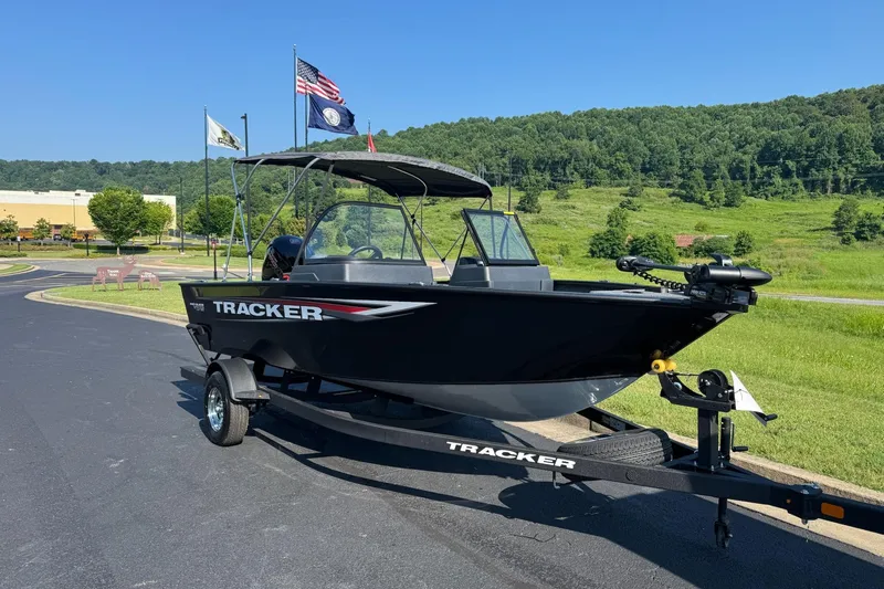 Slide: The Image of 2026 Tracker Pro Guide V-175 WT boat on trailer, parked outdoors with flags and greenery. - 4