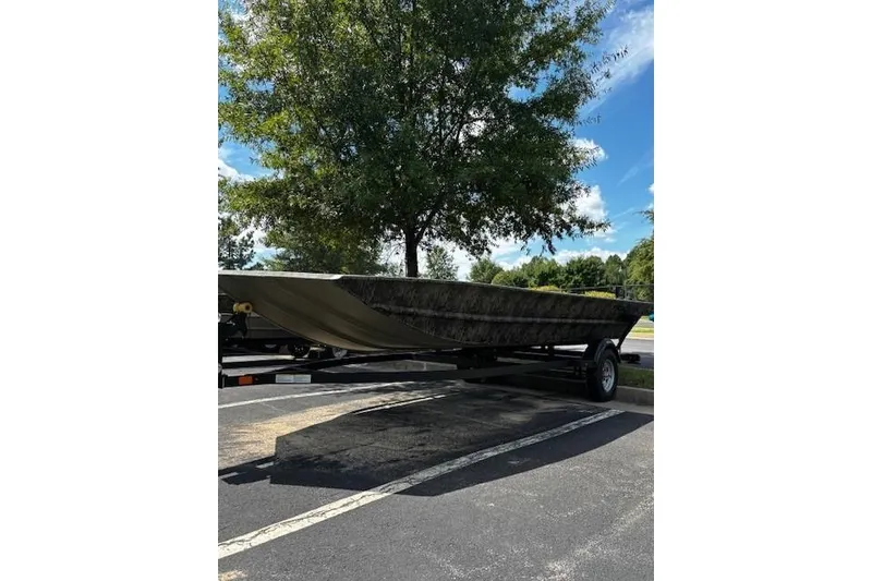 The Image of 2026 Tracker Grizzly 1860 Utility boat on trailer, parked under a tree in a lot. - 0