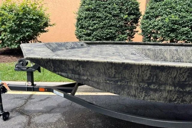 Slide: The Image of 2026 Tracker Grizzly 1860 Utility boat on trailer, camo design, parked outdoors. - 4