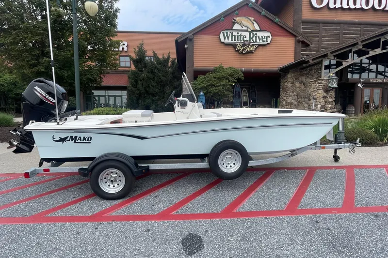 Slide: The Image of 2026 Mako Pro Skiff 17 CC boat on trailer outside store, "We Take Trades" sign. - 0