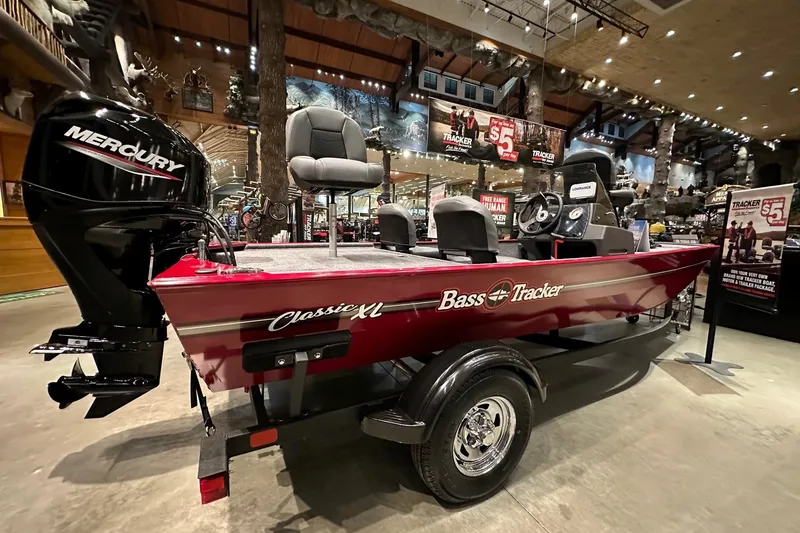 Slide: The Image of 2026 Tracker Bass Tracker Classic XL boat displayed indoors with Mercury engine. - 2