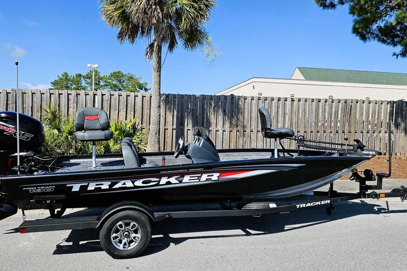 The Image of 2026 Tracker Pro Team 190 boat on trailer, parked outdoors near wooden fence. - 0
