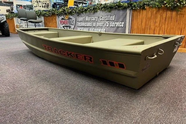 Slide: The Image of 2026 Tracker Grizzly 10 Jon boat displayed indoors, featuring a durable design and olive green color. - 2