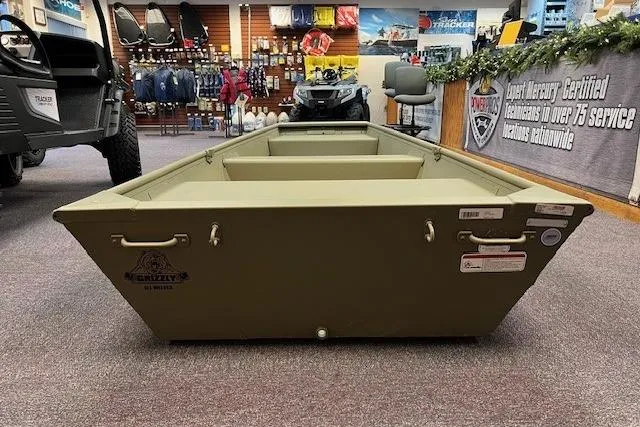 Slide: The Image of 2026 Tracker Grizzly 10 Jon boat displayed in a showroom with various outdoor equipment. - 6