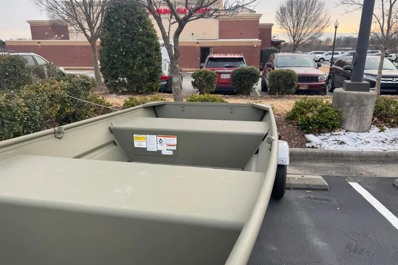 Slide: The Image of 2026 Tracker Grizzly 12 Jon boat parked in a lot near a shopping center. - 4