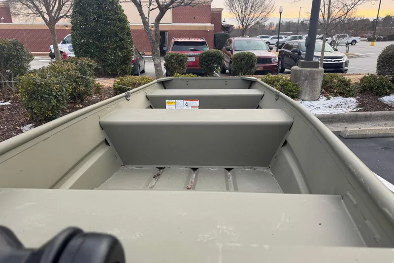 Slide: The Image of 2026 Tracker Grizzly 12 Jon boat in a parking lot, surrounded by cars and trees. - 2