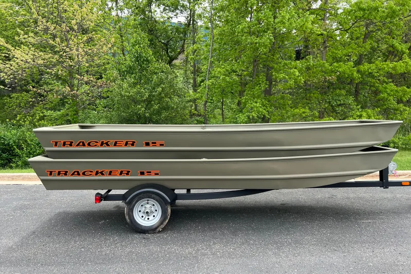 Slide: The Image of 2026 Tracker Grizzly 15 Jon boats stacked on a trailer, surrounded by lush greenery. - 20