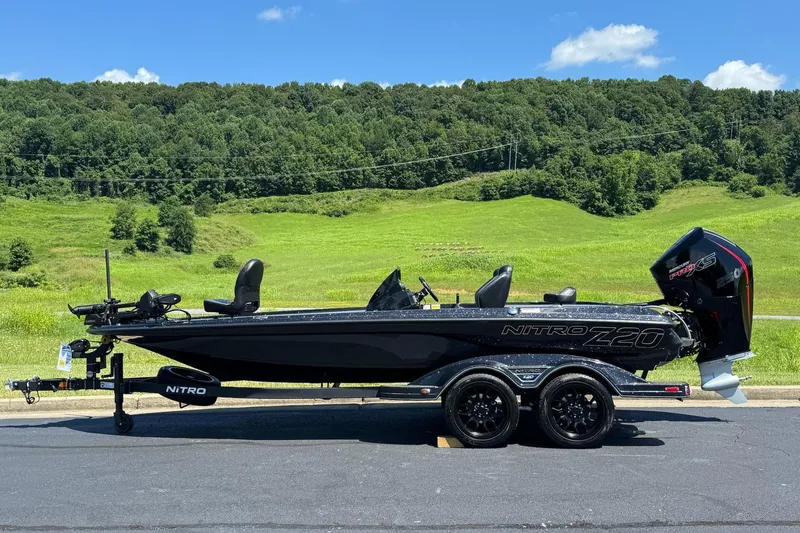The Image of 2026 Nitro Z20 XL Pro boat on trailer, parked on road with lush green landscape. - 0