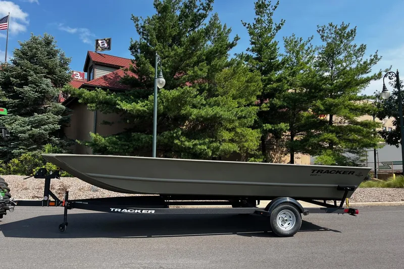 The Image of 2026 Tracker GRIZZLY 2072 Utility boat on trailer, parked near trees and building. - 0