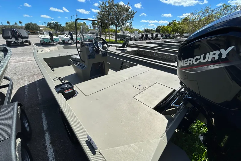 Slide: The Image of 2026 Tracker Grizzly 1860 CC boat with Mercury engine in a sunny parking lot. - 2
