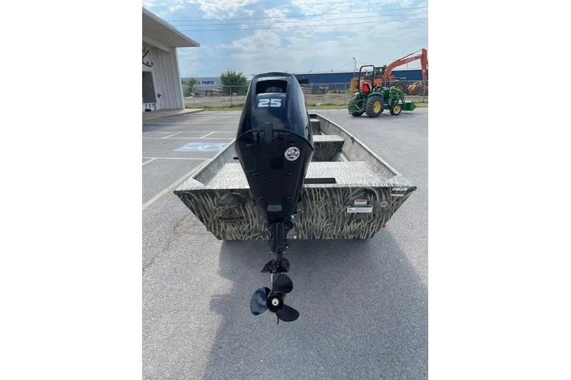 Slide: The Image of 2026 Tracker Grizzly 15 Jon boat with 25HP outboard motor, parked outdoors. - 2