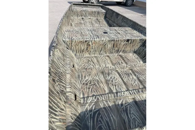 Slide: The Image of 2026 Tracker Grizzly 15 Jon boat with camouflage pattern in a parking lot. - 5