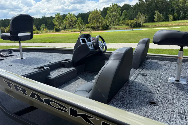 Slide: The Image of 2026 Tracker Pro Team 190 boat interior with seating and steering wheel, set against a scenic outdoor backdrop. - 2