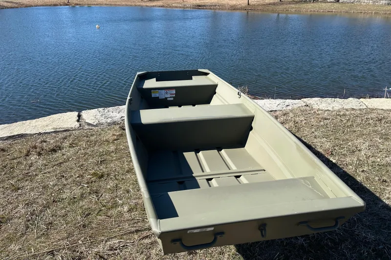 Slide: The Image of 2026 Tracker Grizzly 14 Jon boat by a serene lake. - 3