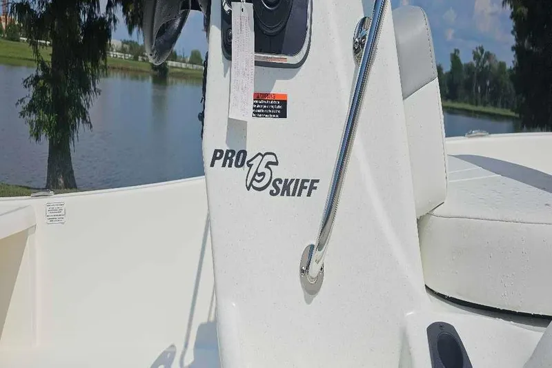Slide: The Image of 2026 Mako Pro Skiff 15 CC boat console by a serene lake. - 2