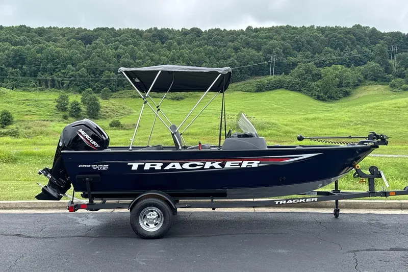 The Image of 2026 Tracker Pro Guide V-16 SC boat on trailer, scenic green landscape background. - 0