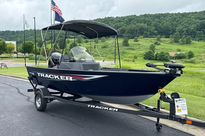 Slide: The Image of 2026 Tracker Pro Guide V-16 SC boat on trailer, parked outdoors with flags in background. - 3