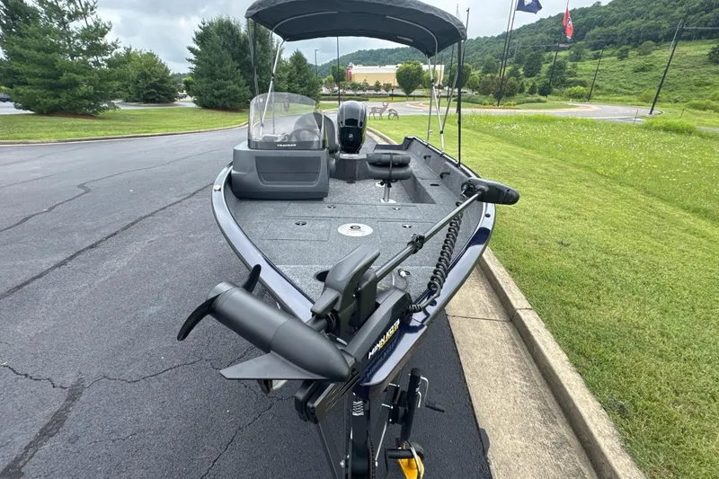 Slide: The Image of 2026 Tracker Pro Guide V-16 SC boat with canopy on paved road, green landscape background. - 4