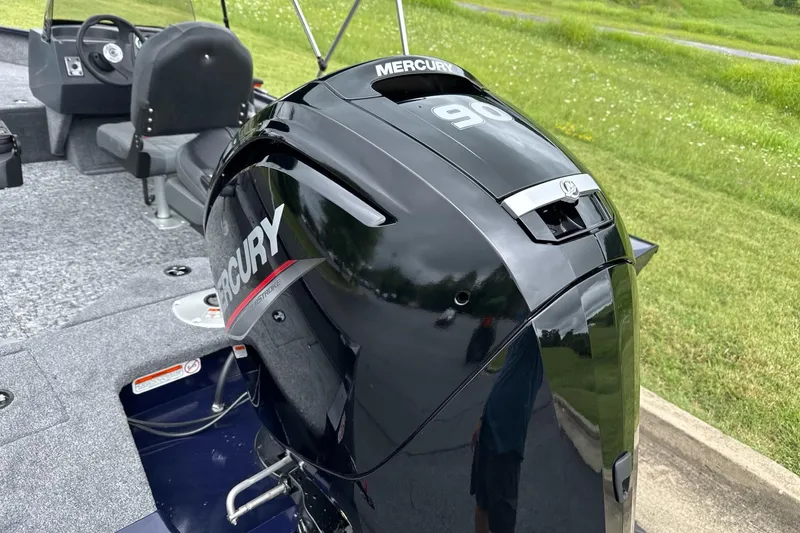 Slide: The Image of 2026 Tracker Pro Guide V-16 SC boat with Mercury 90 engine, gray interior, grassy background. - 7