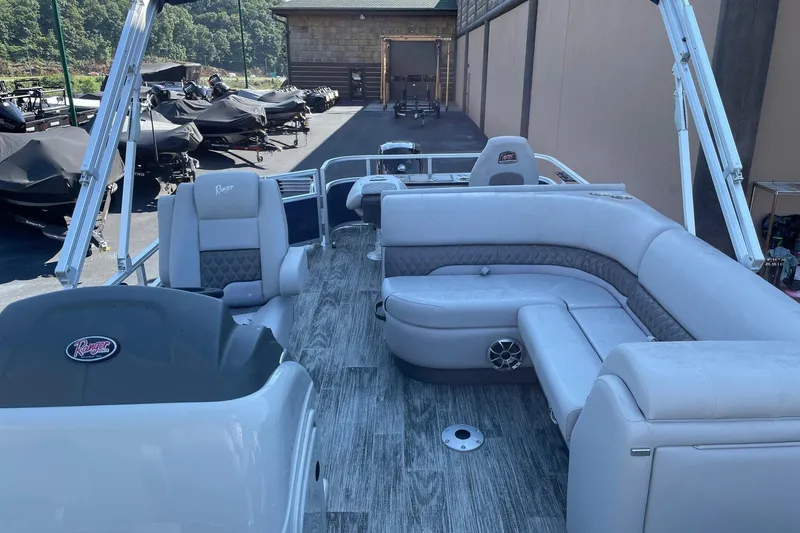 Slide: The Image of 2024 Ranger Reata 220F pontoon boat with Mercury 150 engine, parked outdoors. - 2