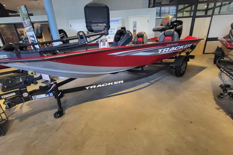 The Image of 2026 Tracker Pro Team 175 boat in showroom, red and gray design, on trailer. - 0
