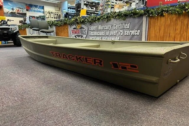 Slide: The Image of 2026 Tracker Grizzly 12 Jon boat displayed in a showroom with promotional banners. - 2